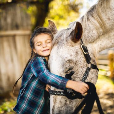 a little girl hugging a horse