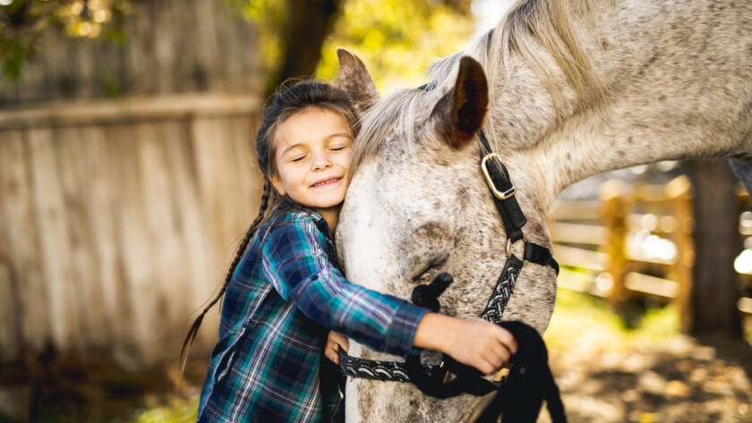 a little girl hugging a horse